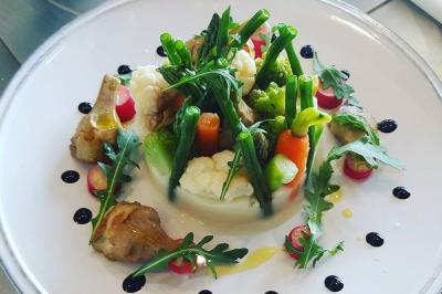 Assiette de légumes variés dressés avec soin, comprenant asperges, carottes, chou-fleur, roquette et sauce décorative.