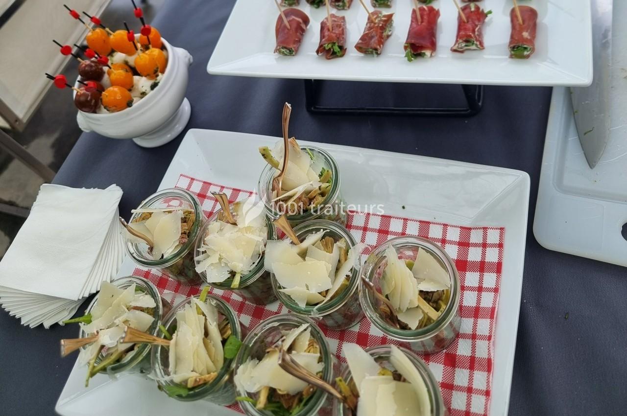 Assortiment d'entrées comprenant verrines de salade, brochettes de tomates cerises et roulés de jambon cru.
