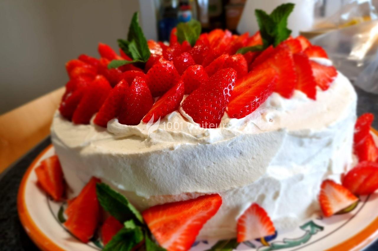 Gâteau recouvert de crème fouettée, décoré de fraises fraîches et de feuilles de menthe.