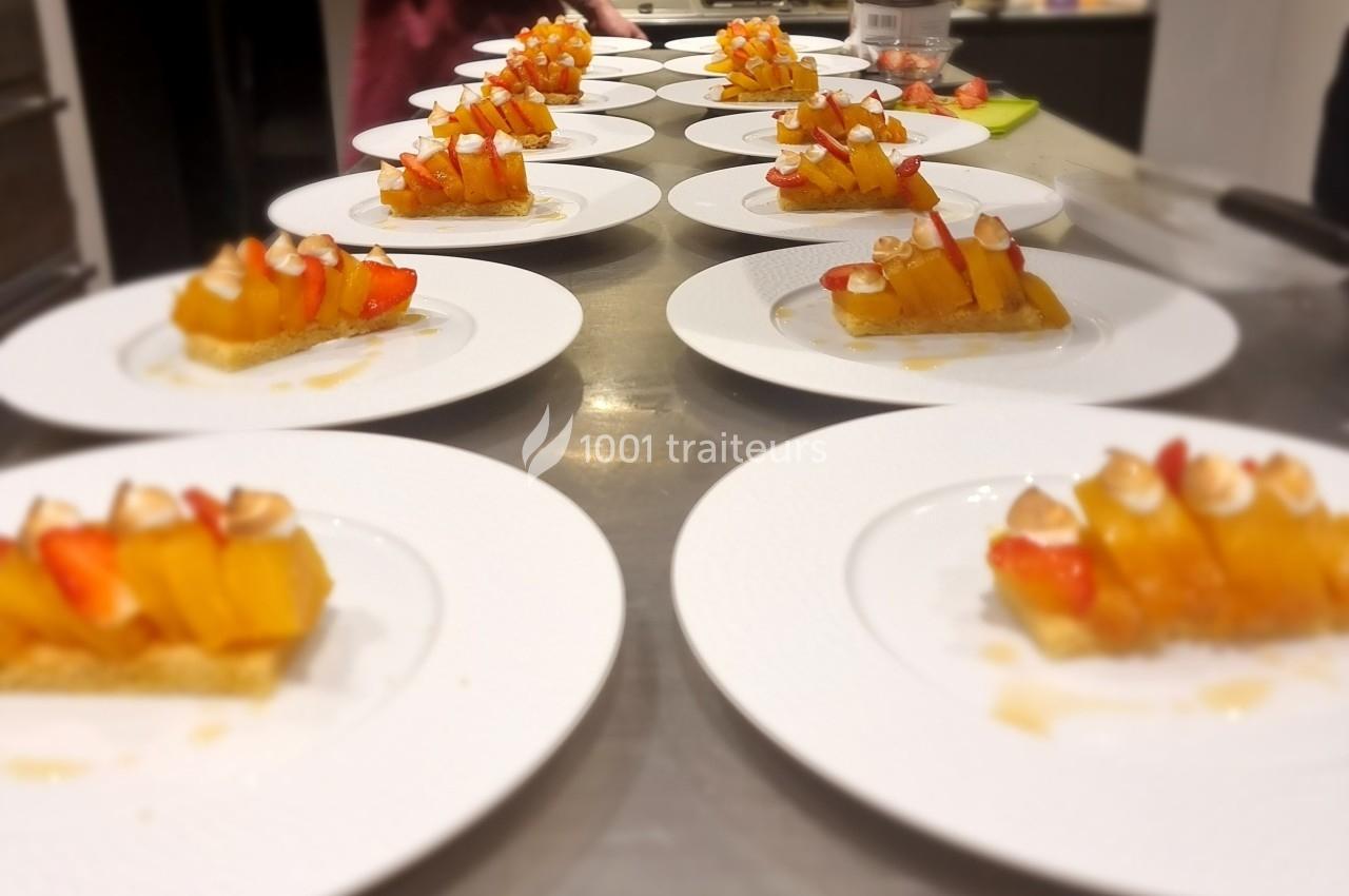 Assiettes alignées contenant des desserts composés de fruits frais et de biscuits, disposées sur un plan de travail.