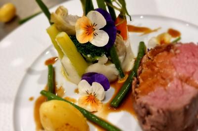 Assiette de légumes variés dressés avec soin, comprenant asperges, carottes, chou-fleur, roquette et sauce décorative.