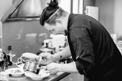 Assiette de légumes variés dressés avec soin, comprenant asperges, carottes, chou-fleur, roquette et sauce décorative.