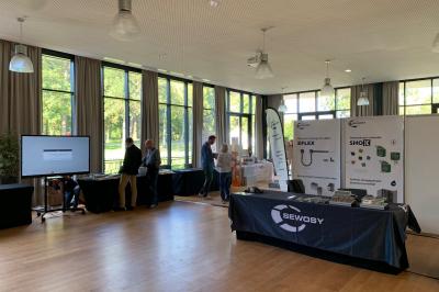 Un homme en costume noir et baskets blanches pointe du doigt sur une scène éclairée par des projecteurs.