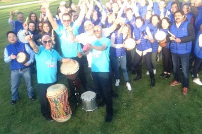 Deux personnes assises dans un buggy bleu en extérieur, discutant et manipulant des objets, avec un homme debout à côté.