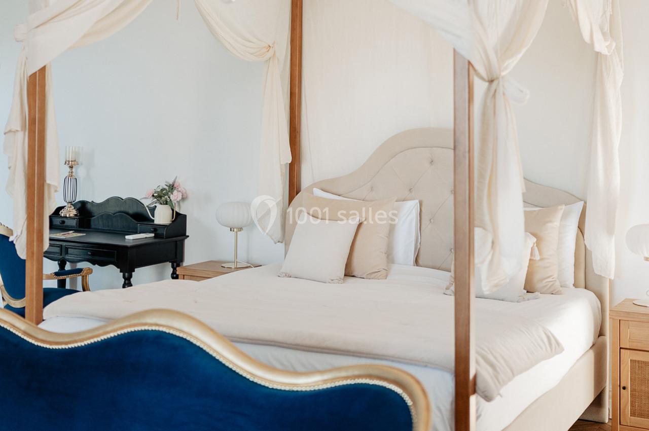 Lit à baldaquin avec drapés blancs dans une chambre lumineuse, décorée avec un bureau noir et des meubles élégants.