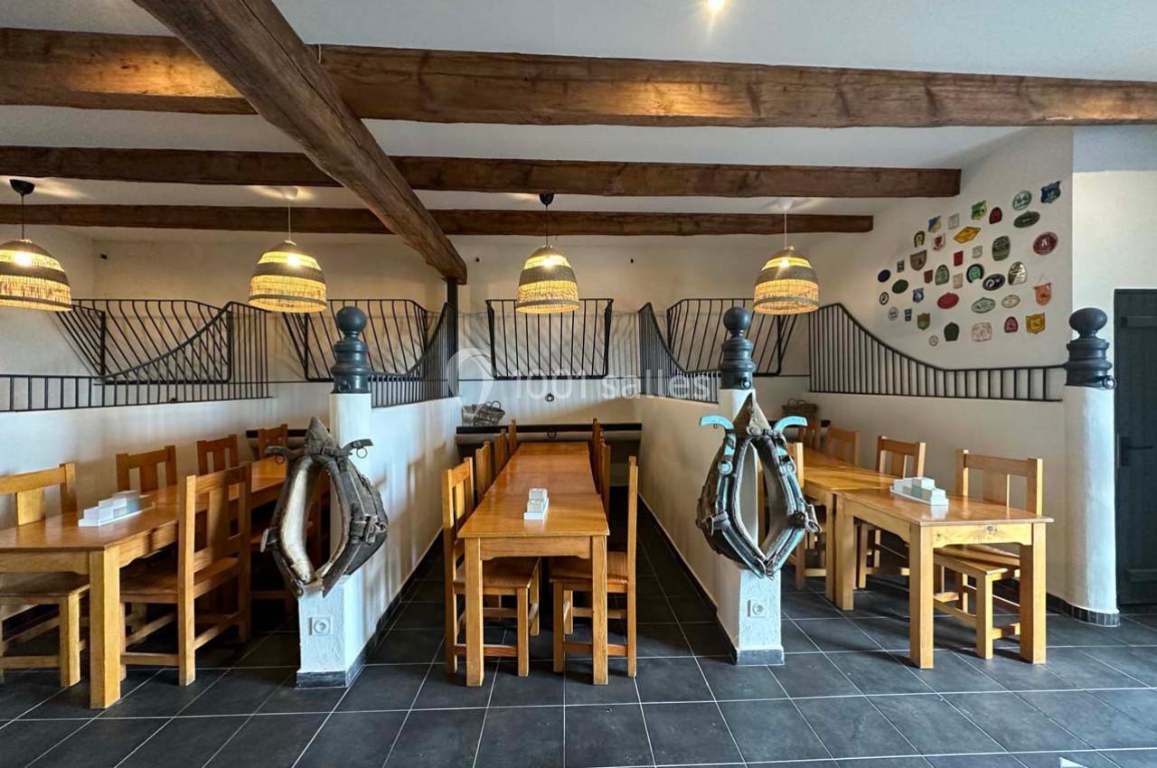 Salle de restaurant avec tables et chaises en bois, décor marin et poutres apparentes au plafond.