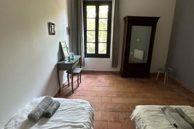 Miniature Location salle Agde (Hérault) - Domaine des Barrettes  #25 Chambre lumineuse avec deux lits simples, un bureau, une armoire en bois et une fenêtre donnant sur un jardin.