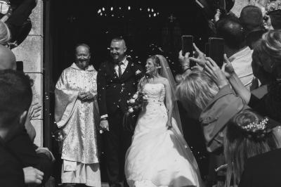 Salle décorée pour un événement avec des tables dressées en noir, rouge et blanc, et des chaises assorties.