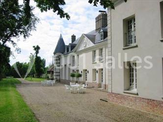 Miniature Location salle Saint-Aubin-sur-Gaillon (Eure) - Château de Beauchêne #11 Cheminée en pierre avec poutres en bois apparentes, ornée d'une composition florale dans une pièce lumineuse.