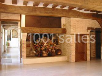 Cheminée en pierre avec poutres en bois apparentes, ornée d'une composition florale dans une pièce lumineuse.