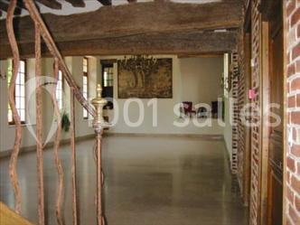 Miniature Location salle Saint-Aubin-sur-Gaillon (Eure) - Château de Beauchêne #13 Cheminée en pierre avec poutres en bois apparentes, ornée d'une composition florale dans une pièce lumineuse.