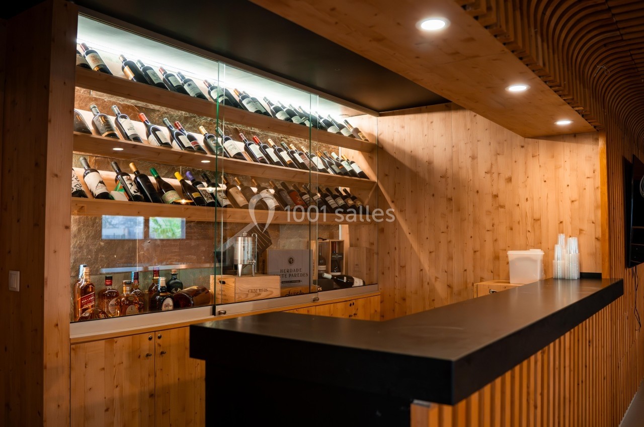 Étagères en bois avec des bouteilles de vin exposées derrière un comptoir noir dans un espace éclairé.