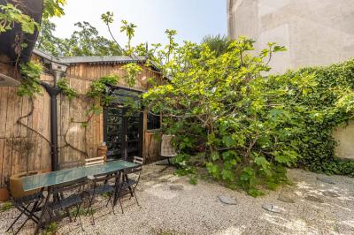 Miniature Location salle Paris 18 (Paris) - Loft Montmartre #1 Balcon étroit avec sol en bois, mur en pierre, grillage métallique et vue sur un jardin arboré.