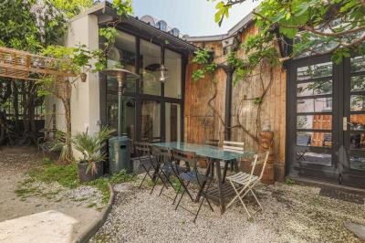Miniature Location salle Paris 18 (Paris) - Loft Montmartre #2 Balcon étroit avec sol en bois, mur en pierre, grillage métallique et vue sur un jardin arboré.