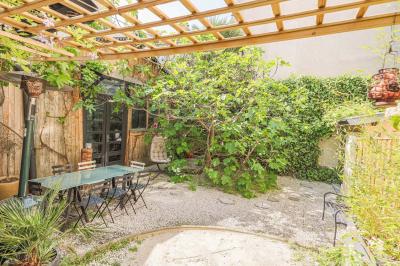 Miniature Location salle Paris 18 (Paris) - Loft Montmartre #3 Balcon étroit avec sol en bois, mur en pierre, grillage métallique et vue sur un jardin arboré.