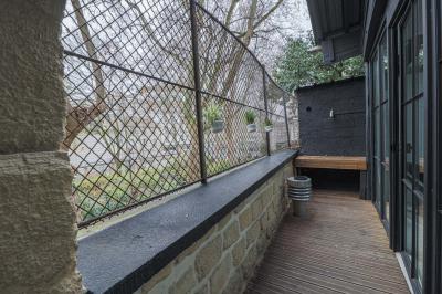 Miniature Location salle Paris 18 (Paris) - Loft Montmartre #13 Balcon étroit avec sol en bois, mur en pierre, grillage métallique et vue sur un jardin arboré.