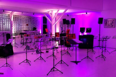 Groupe de personnes dans une ambiance festive, éclairage coloré et musique en arrière-plan.