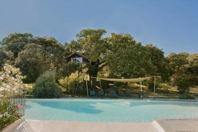Vue aérienne d'une grande maison en pierre avec piscine, entourée de forêts et de champs sous un ciel dégagé.