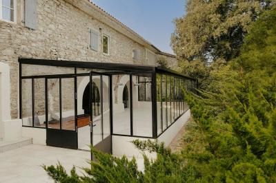 Vue aérienne d'une grande maison en pierre avec piscine, entourée de forêts et de champs sous un ciel dégagé.
