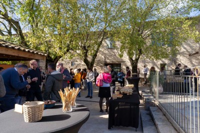 Vue aérienne d'une grande maison en pierre avec piscine, entourée de forêts et de champs sous un ciel dégagé.