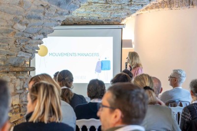 Vue aérienne d'une grande maison en pierre avec piscine, entourée de forêts et de champs sous un ciel dégagé.