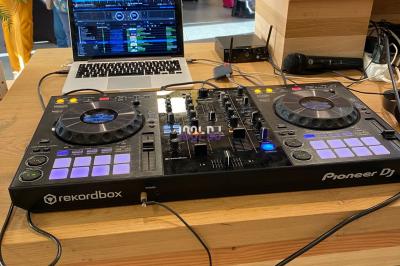 Table de mixage Pioneer DJ avec ordinateur portable ouvert, installée sur un comptoir en bois lors d'un événement.
