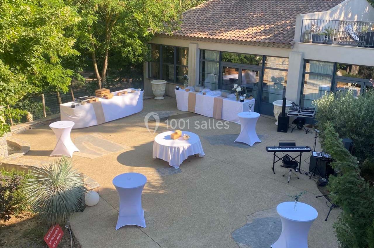 Terrasse aménagée pour un événement avec tables hautes, buffets dressés et équipements de musique en extérieur.