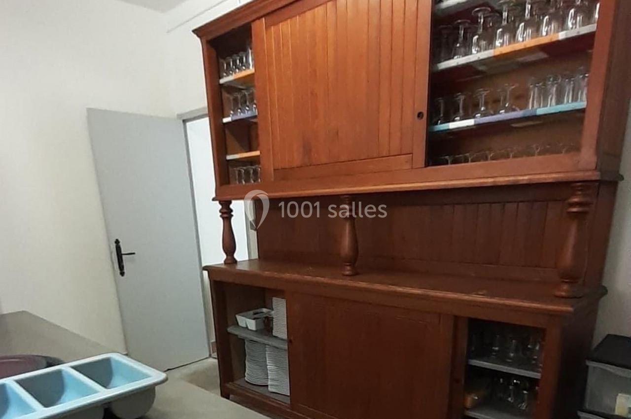 Buffet en bois avec portes vitrées contenant des verres, situé dans une pièce avec un évier et une porte blanche.