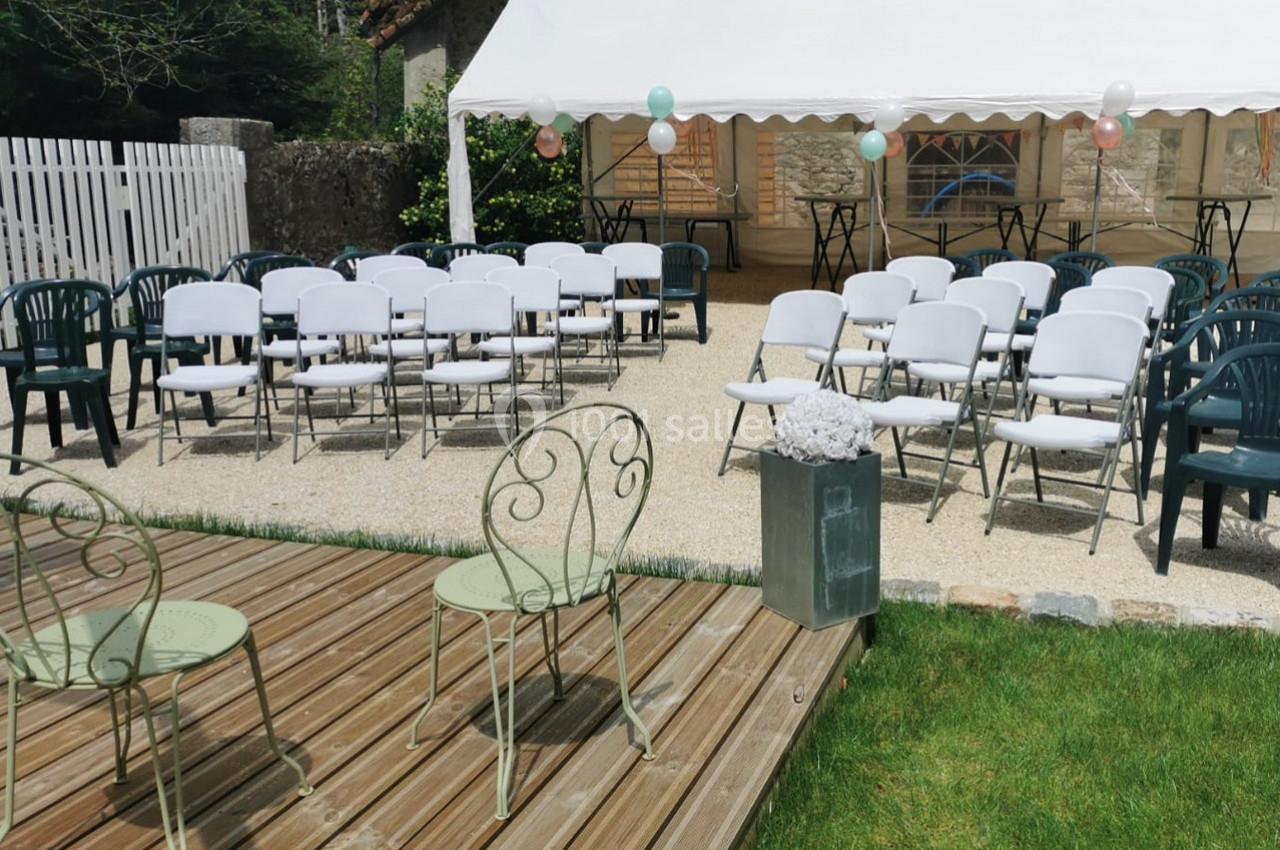 Chaises blanches et vertes disposées devant une tente blanche dans un jardin, préparées pour un événement en extérieur.