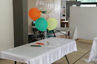 Serviettes pliées en forme de fleurs, orange et bleue, disposées sur des verres transparents sur une table en bois.
