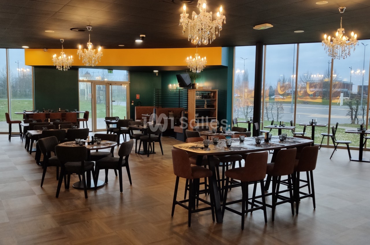 Salle de restaurant moderne avec tables dressées, chaises en cuir, lustres suspendus et grandes baies vitrées.