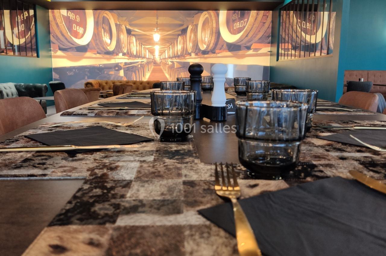 Table dressée avec des verres, couverts dorés et serviettes noires, dans un restaurant à la décoration chaleureuse.