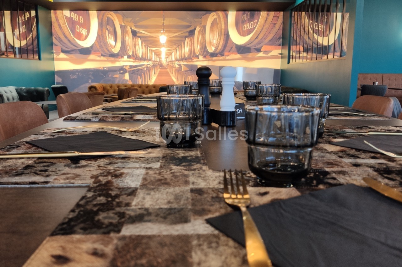 Table dressée avec des verres, couverts dorés et serviettes noires, dans un restaurant à la décoration chaleureuse.