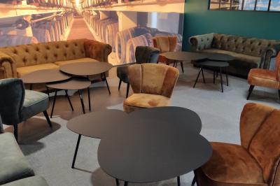 Bar moderne avec comptoir en marbre noir, étagères remplies de verres et bouteilles, machine à café et écran allumé.