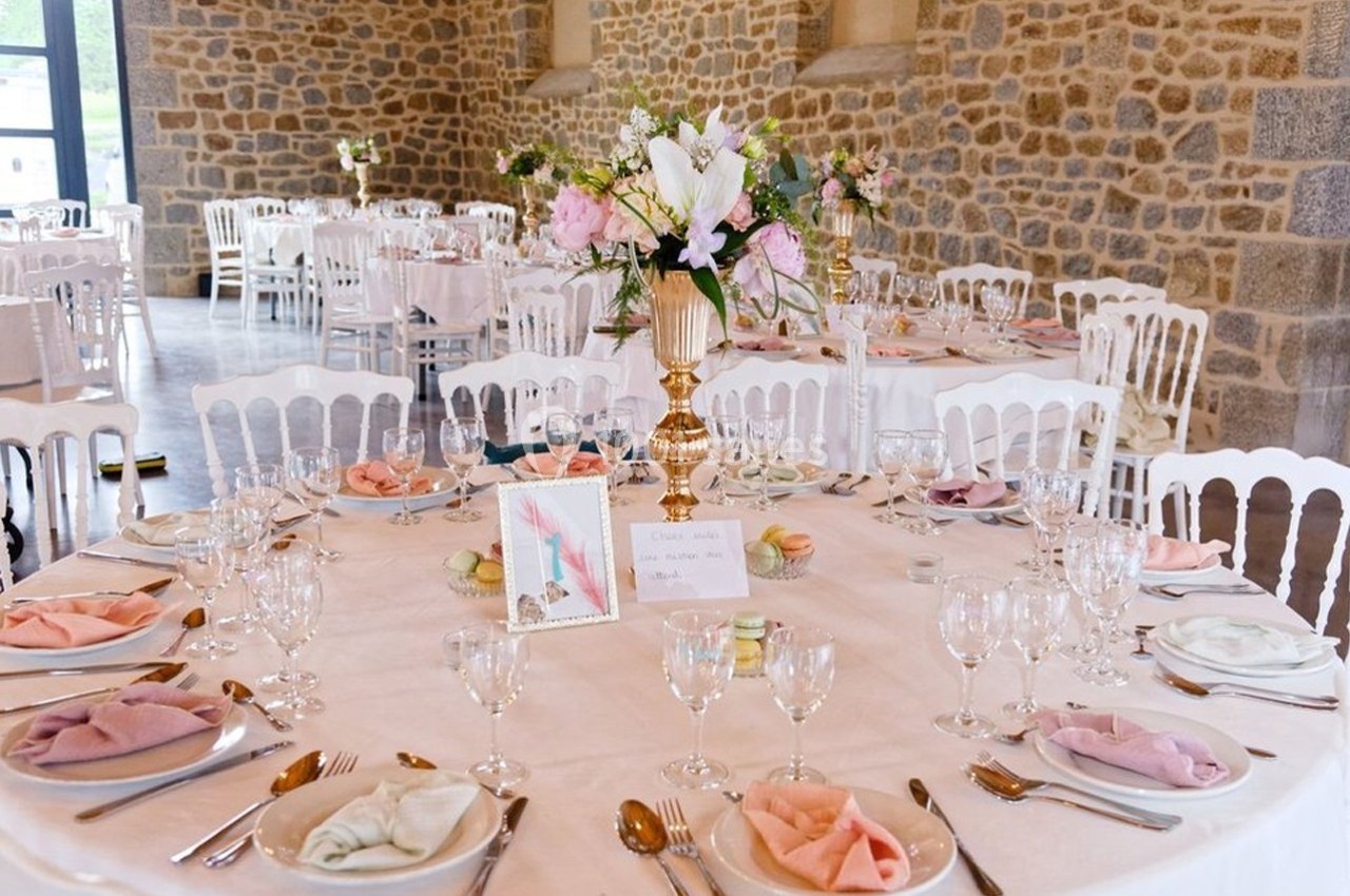 Table de réception élégamment dressée avec nappes blanches, serviettes colorées, vaisselle raffinée et centre de table…