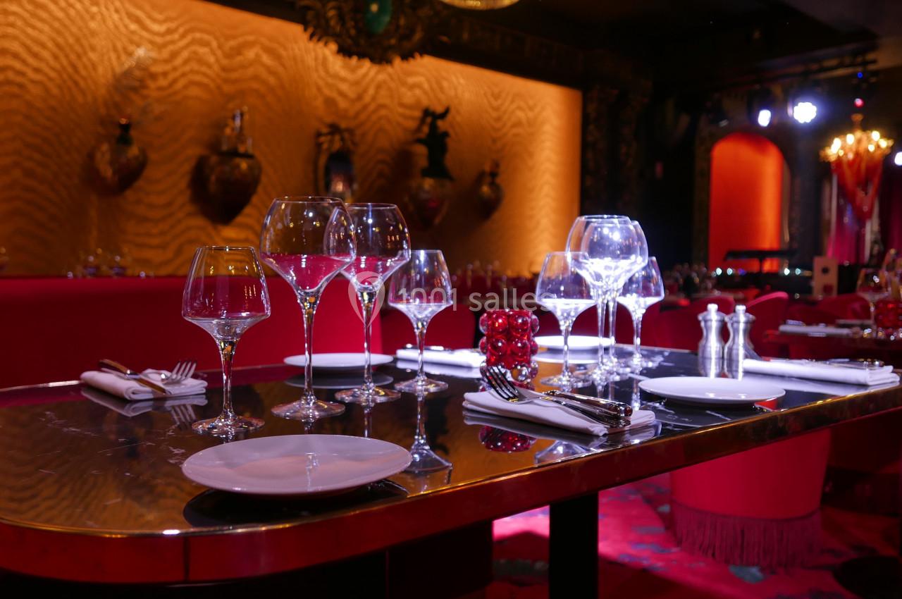 Table élégamment dressée avec verres, assiettes et couverts, dans un restaurant à l'ambiance tamisée et chaleureuse.