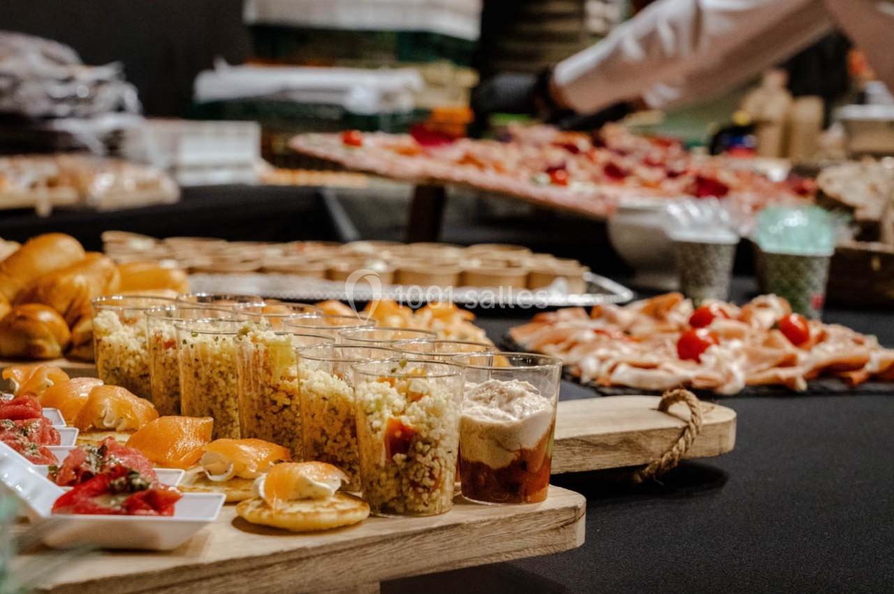 Buffet varié avec verrines, pains, charcuteries et amuse-bouches disposés sur une table noire.