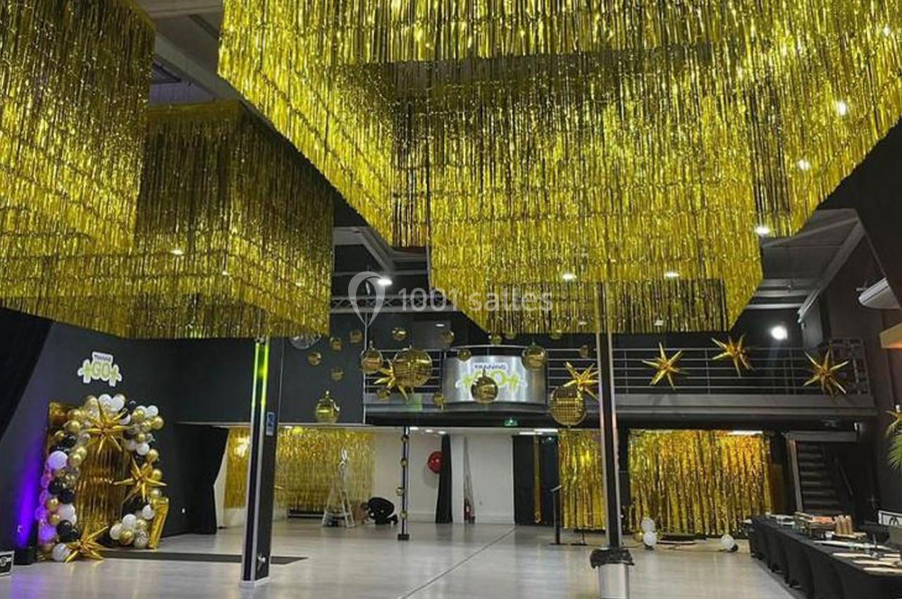 Salle décorée avec des guirlandes dorées suspendues, des ballons et des étoiles, prête pour un événement festif.