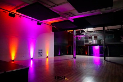 Salle de détente avec fauteuils variés, table basse, tapis géométrique et éclairage tamisé.