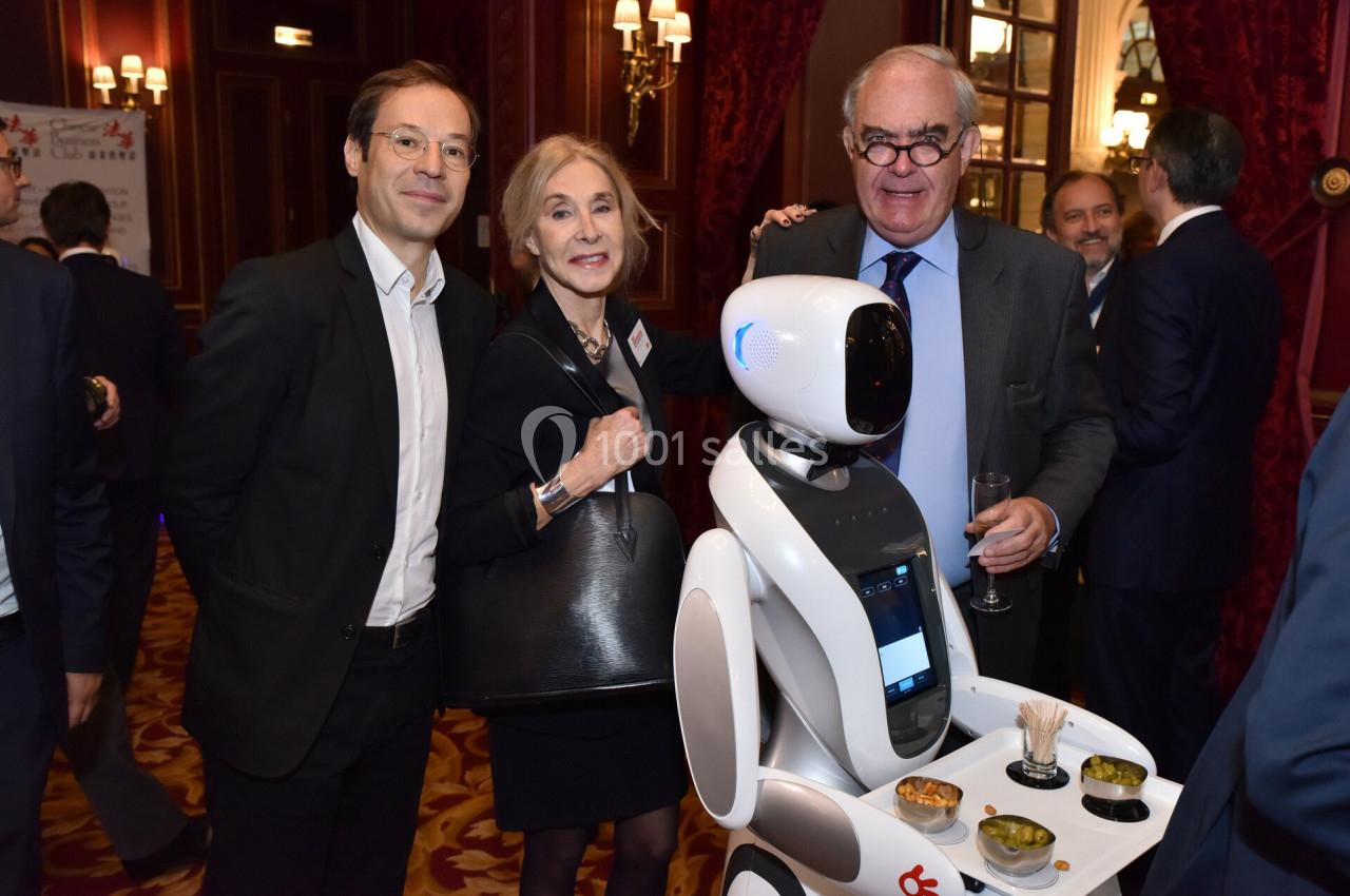 Un robot interactif présenté lors d'un événement, entouré de trois personnes souriantes dans un cadre élégant.
