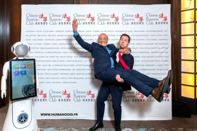 Robot humanoïde blanc équipé d'un écran et d'un plateau, présenté dans un environnement intérieur avec plantes et…