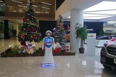 Robot humanoïde blanc équipé d'un écran et d'un plateau, présenté dans un environnement intérieur avec plantes et…