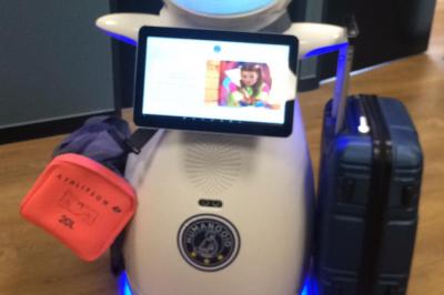 Robot humanoïde blanc équipé d'un écran et d'un plateau, présenté dans un environnement intérieur avec plantes et…