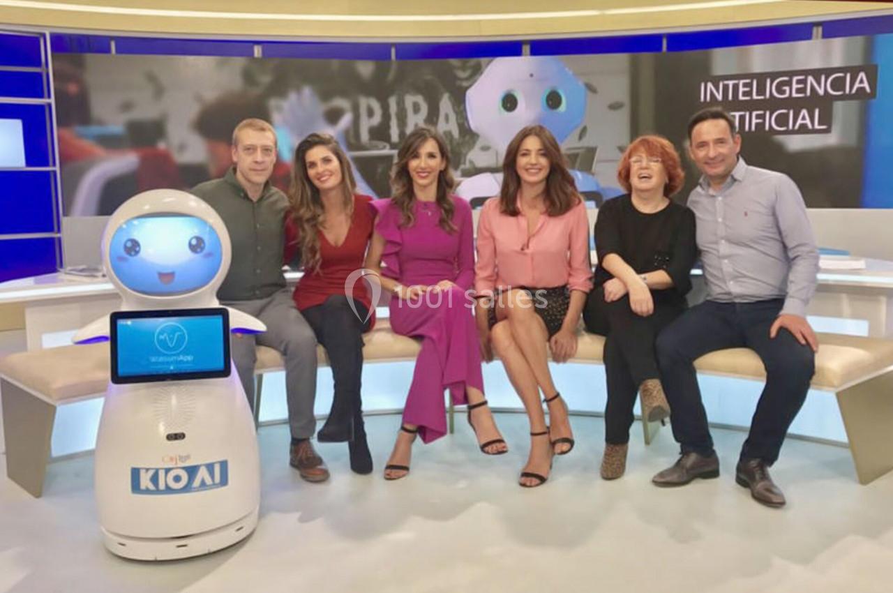 Un groupe de personnes assises sur un canapé avec un robot interactif dans un studio télévisé.