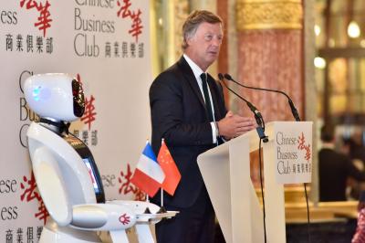 Robot humanoïde blanc équipé d'un écran et d'un plateau, présenté dans un environnement intérieur avec plantes et…