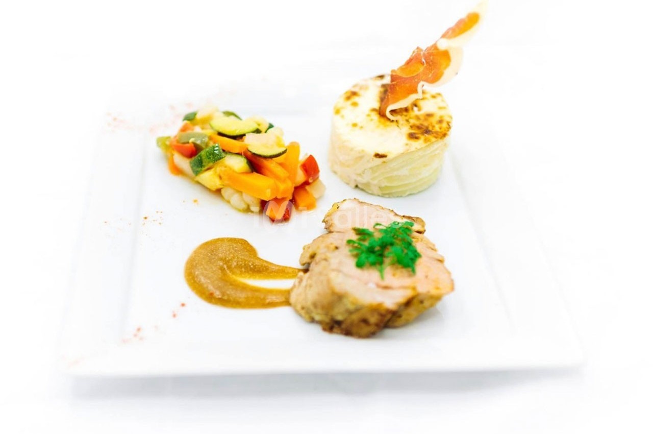 Assiette gastronomique avec filet de viande, purée gratinée, légumes colorés et sauce servie sur une assiette blanche.