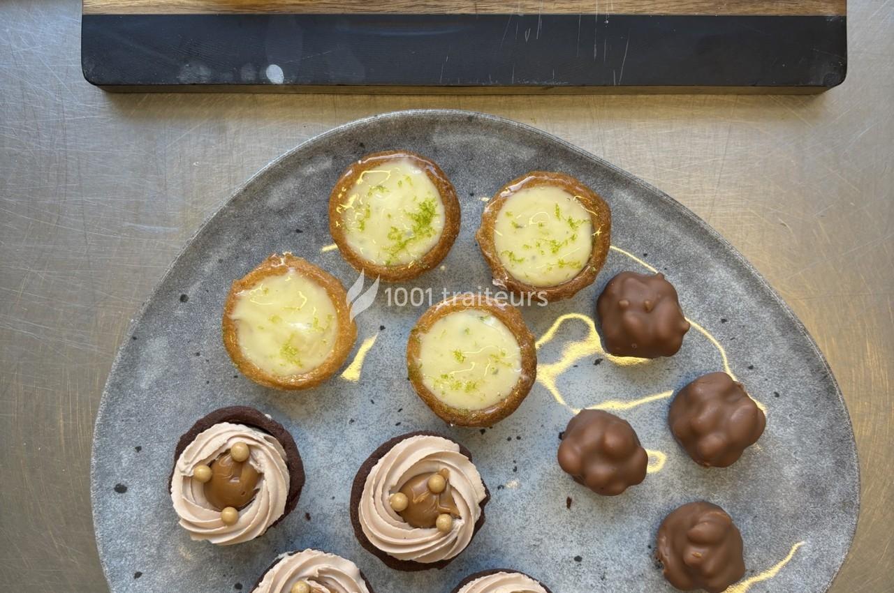 Assortiment de desserts sur une assiette : tartelettes, cupcakes au chocolat et bouchées enrobées, avec un roulé au chocolat.