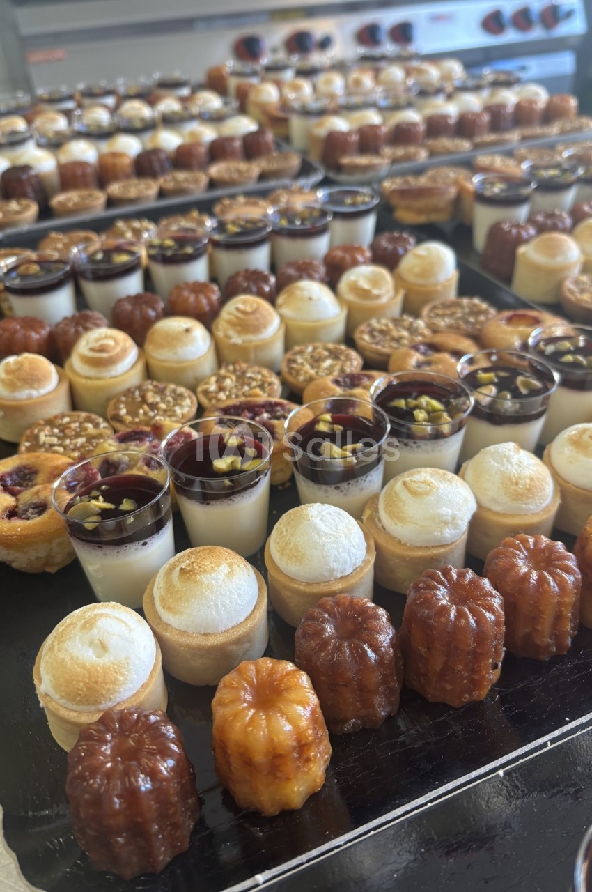 Plateau de desserts variés comprenant cannelés, verrines, tartelettes et autres pâtisseries miniatures.