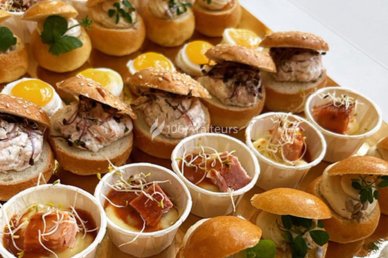 Plateau de mini-burgers, verrines et bouchées garnies de poisson, œufs et herbes fraîches.