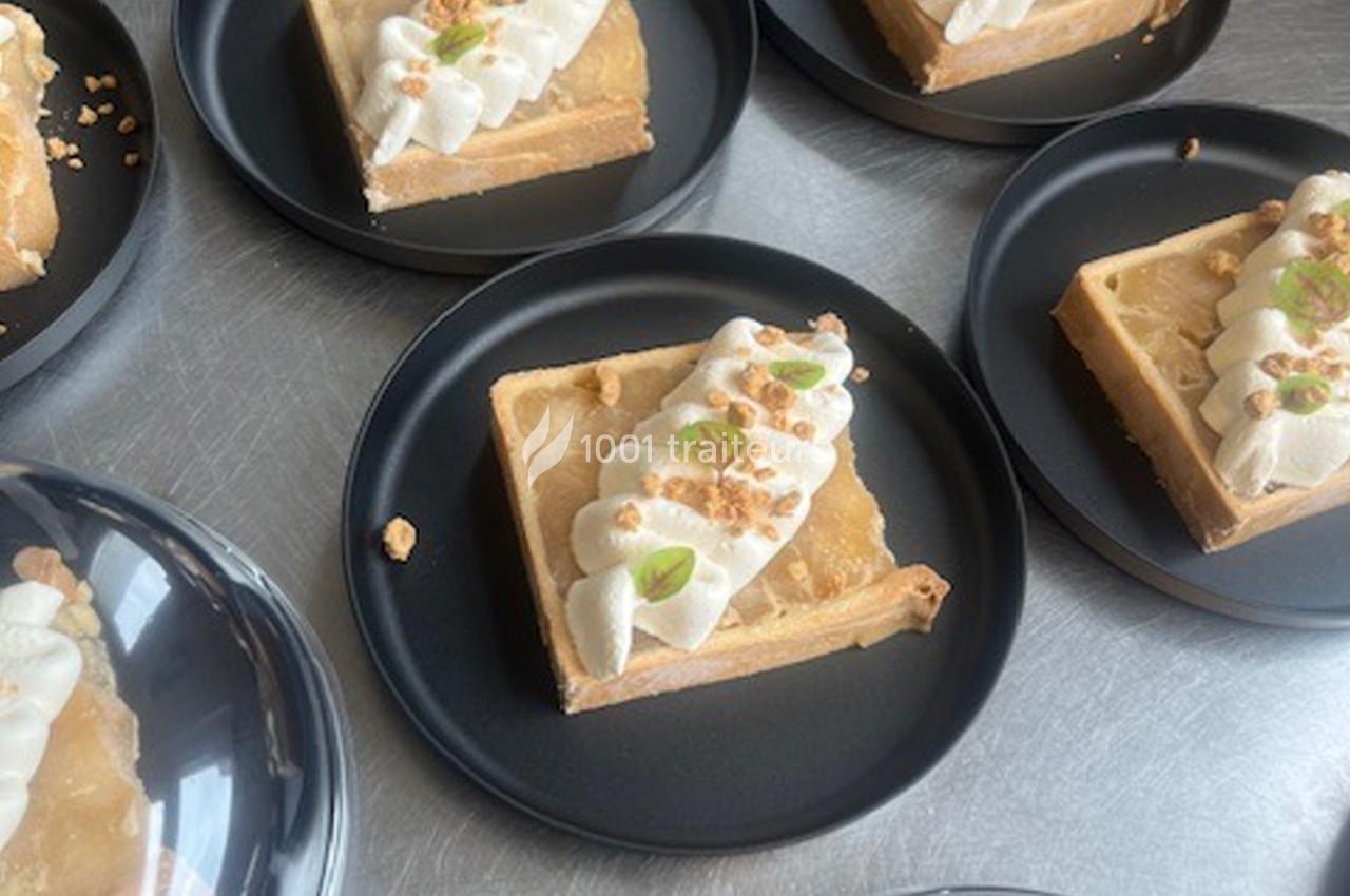 Parts de tarte garnies de crème fouettée, éclats de noix et zestes, présentées sur des assiettes noires.